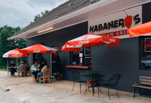 Outdoor seating area of Habanero's Mexican Grill, featuring red umbrellas and patrons enjoying their meals.