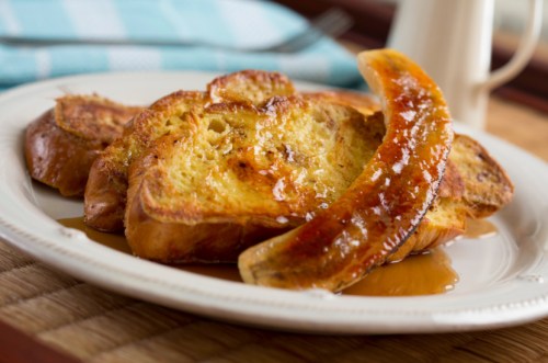 A plate of French toast topped with caramelized banana and drizzled with syrup.