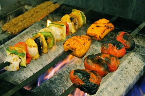 Grilled skewers of colorful vegetables and meat cooking over an open flame.
