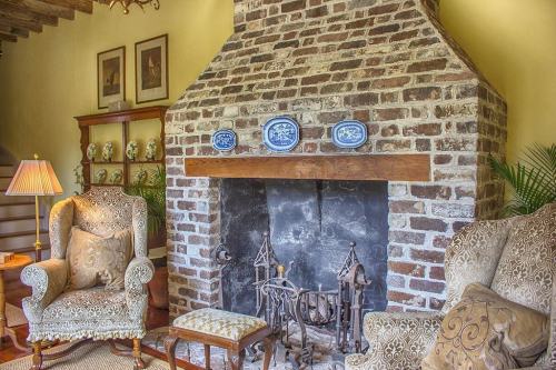 Cozy living room featuring a brick fireplace, two armchairs, and decorative plates on the mantel.