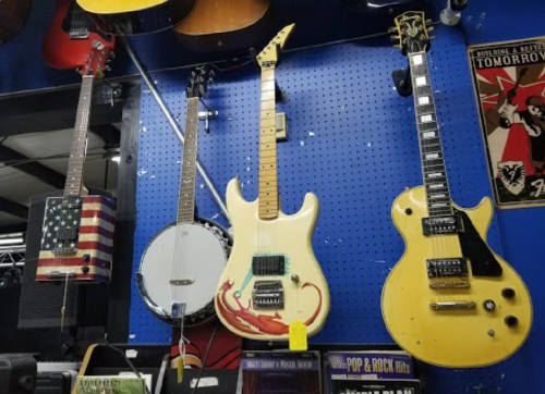 A display of four guitars, including an electric guitar, a banjo, and a guitar with an American flag design.