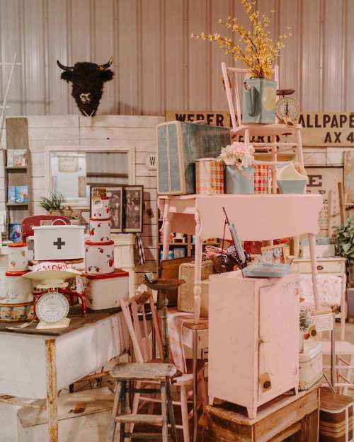 A vintage shop display featuring stacked furniture, decor items, and a decorative bull's head on the wall.