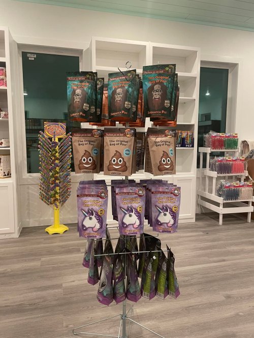 A display of novelty candy products, including poop and unicorn-themed treats, in a brightly lit store.