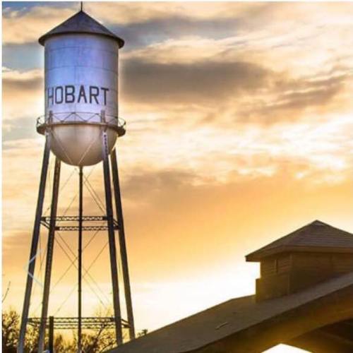 A water tower labeled "HOBART" stands against a vibrant sunset sky.