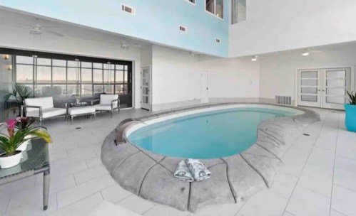 Indoor pool area with a curved edge, surrounded by modern seating and large windows, offering a bright, airy atmosphere.