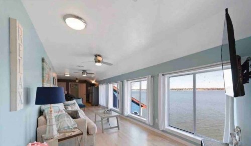 Cozy living room with a view of the water, featuring a sofa, lamp, and large windows letting in natural light.