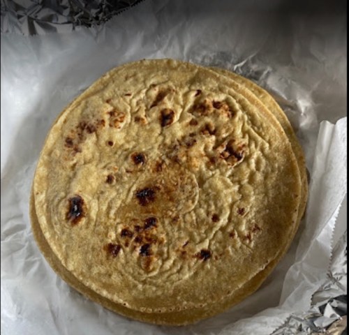 A stack of golden-brown tortillas resting on a piece of parchment paper.