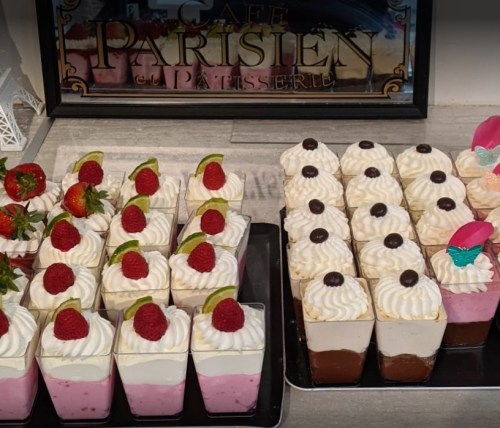 A display of desserts featuring layered mousse cups topped with whipped cream, strawberries, raspberries, and chocolate.