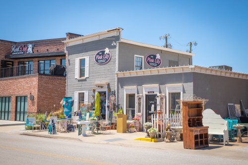 A charming storefront with colorful decor and outdoor displays, featuring the sign "Pink Lily" on a sunny day.