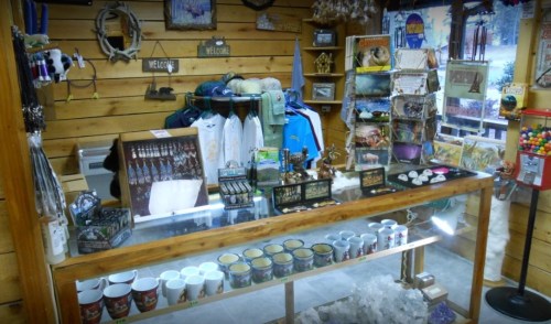 A cozy gift shop display featuring souvenirs, clothing, and snacks in a wooden interior.