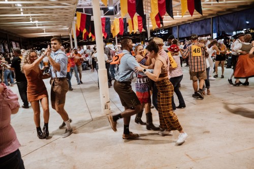 A lively dance floor with people in festive attire enjoying a group dance at a celebration or festival.