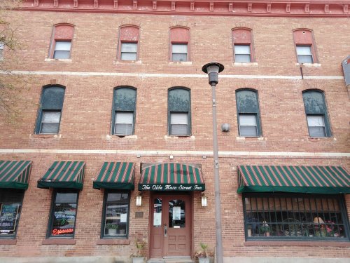 Brick building with green and red striped awnings, featuring a sign for "The Olde Kettle Street Inn" and large windows.