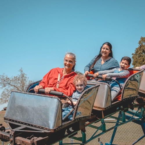 A group of four people, including two children, enjoying a ride on a roller coaster at an amusement park.