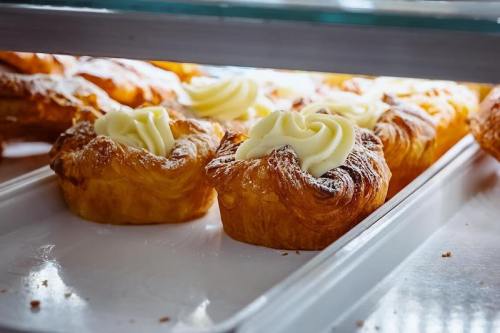 Freshly baked pastries with creamy frosting displayed in a bakery case.