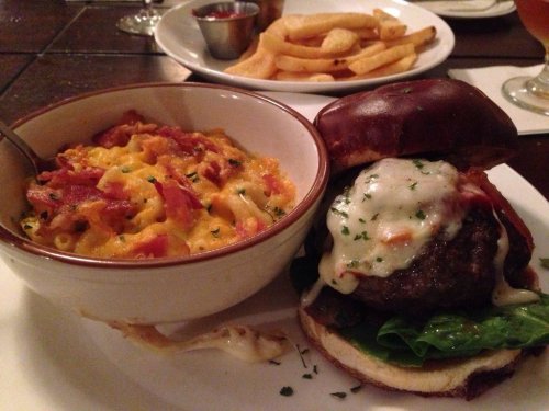 A juicy burger with melted cheese and lettuce, served with a side of creamy macaroni and cheese and French fries.