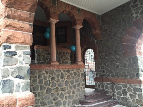 Stone entrance with arched columns and blue balloons, featuring a mix of textured stone and brick walls.