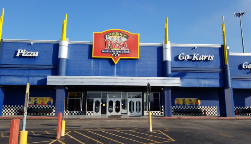 Exterior of Incredible Pizza in Conroe, featuring a colorful sign and sections for pizza and go-karts.