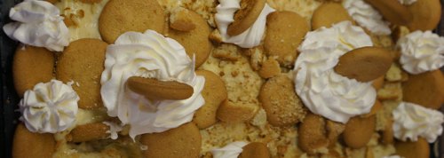A dessert topped with whipped cream, vanilla wafers, and crumbled cake, creating a creamy and sweet appearance.