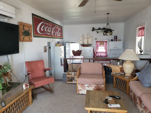 Cozy living room with vintage decor, including a Coca-Cola sign, nautical elements, and comfortable seating.