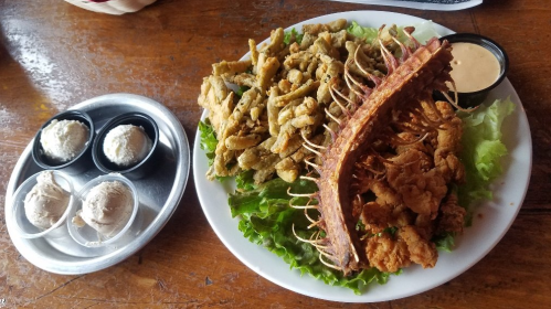 A plate of fried seafood and chicken on lettuce, accompanied by two scoops of ice cream in small cups.