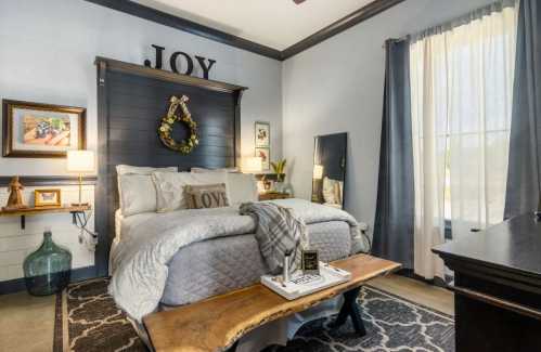 Cozy bedroom with a gray and white color scheme, featuring a bed, decorative pillows, and a wooden bench.