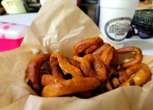 A basket of golden-brown pretzel bites on parchment paper, with a cup in the background.