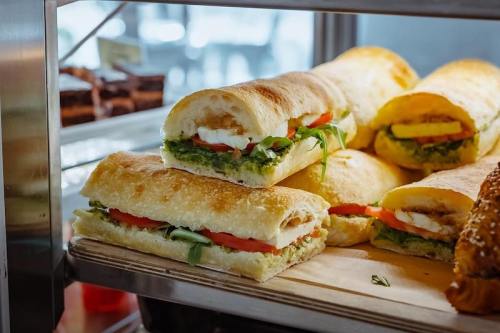 A display of fresh sandwiches with layers of lettuce, tomato, and creamy filling on crusty bread.