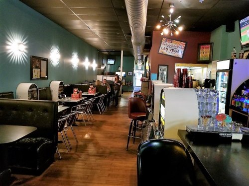 A cozy diner interior with booths, tables, and a bar area, featuring retro decor and a warm atmosphere.