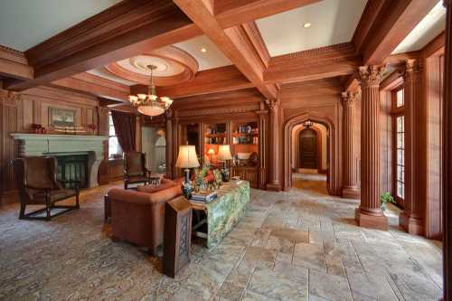 Luxurious living room with wooden beams, elegant furniture, a fireplace, and a cozy reading nook.