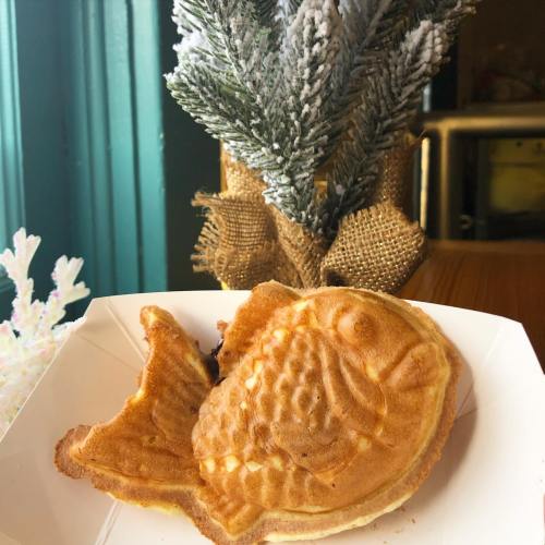 A fish-shaped waffle on a white plate, with a small decorative tree in the background.