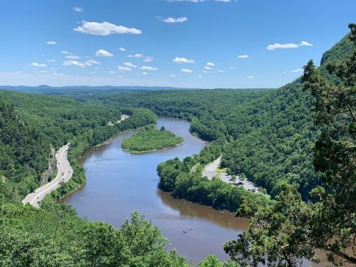 A scenic view of a winding river surrounded by lush green hills under a clear blue sky.