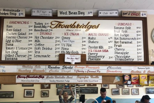 Menu board at Trowbridge's featuring sandwiches, drinks, ice cream, and sundae options with prices listed.