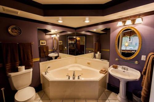 A stylish bathroom featuring a corner bathtub, sink, and decorative mirrors with purple walls and elegant lighting.