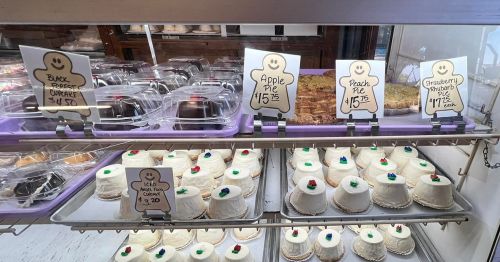 Display case filled with various desserts, including pies and cakes, with price tags visible for each item.