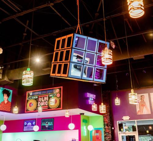 A vibrant interior with colorful walls, unique hanging lights, and a large cube display featuring various images.