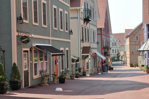 Charming street lined with colorful buildings, planters, and flags, creating a quaint, inviting atmosphere.