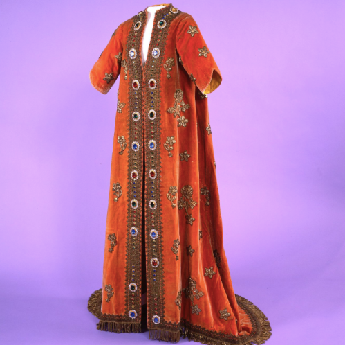 A vibrant red robe adorned with intricate embroidery and decorative stones, displayed against a purple background.