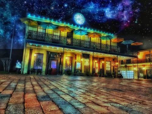 A vibrant building with a starry sky backdrop, featuring colorful lights and a cobblestone path in the foreground.