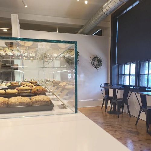 A cozy café interior featuring a display case of cookies and a small seating area by the window.