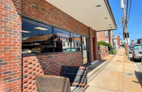 Exterior of a brick building with large windows, featuring a sign that reads "Missouri Bounty," on a sunny day.