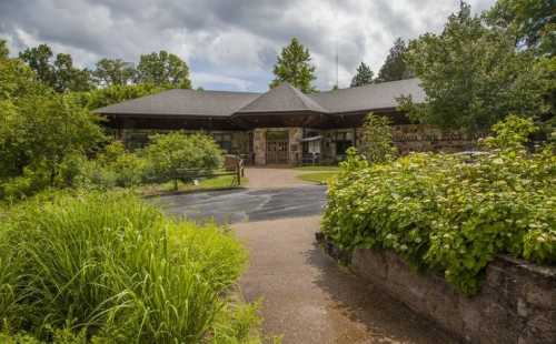 A nature center building surrounded by lush greenery and trees under a cloudy sky.