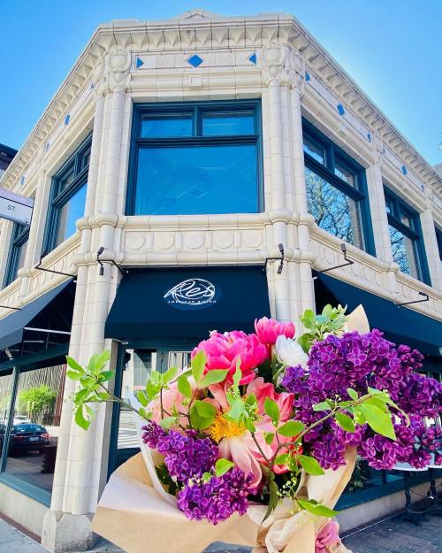 A corner building with large windows and a sign, featuring a bouquet of colorful flowers in the foreground.