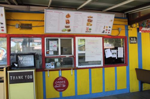 A colorful food stand with a menu above, featuring burgers and snacks, and a sign for ordering at the counter.