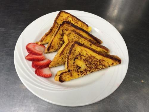 A plate of golden-brown French toast slices served with fresh strawberry halves.