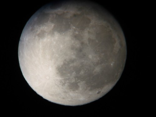 A close-up view of the moon, showcasing its craters and surface details against a black background.