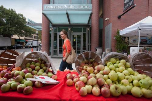 A woman walks past baskets of apples at a market outside the Princeton Public Library.