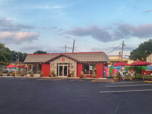 A colorful restaurant with outdoor seating, surrounded by vibrant murals and a clear blue sky.