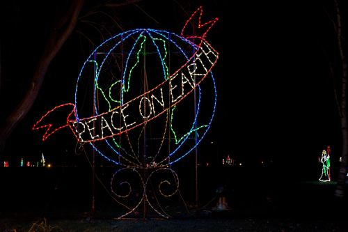 A colorful light display featuring the words "Peace on Earth" surrounded by a globe design at night.