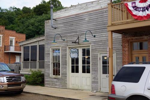 A rustic wooden building with a sign reading "Amanda's Cantina," featuring outdoor seating and nearby parked cars.