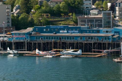 A waterfront scene featuring seaplanes docked at a blue building with a sign for tours, surrounded by greenery.